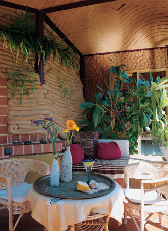 
The light-filled sunroom leads to the back garden. The room features two different styles of clay work—coils and daubs of mud.

